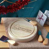 Personalised festive themed round cheeseboard showing a set of cheese utensils. Engraved with a christmas tree icon and the message "The Wilson Family, Christmas Cheese Board".