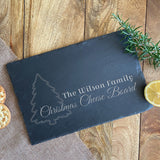 Personalised rectangle slate chopping board. Pictured featuring a festive design with a Christmas tree and the words 'The Wilson Family, Christmas Cheese Board' engraved.