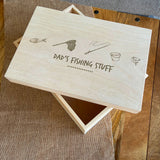 A wooden storage box with the words "dad's fishing stuff" engraved on the lid.