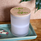 A view of the birthday candle with its bamboo lid on top. The Bamboo lid has two branches of green leaves surrounding the words "Happy Birthday".