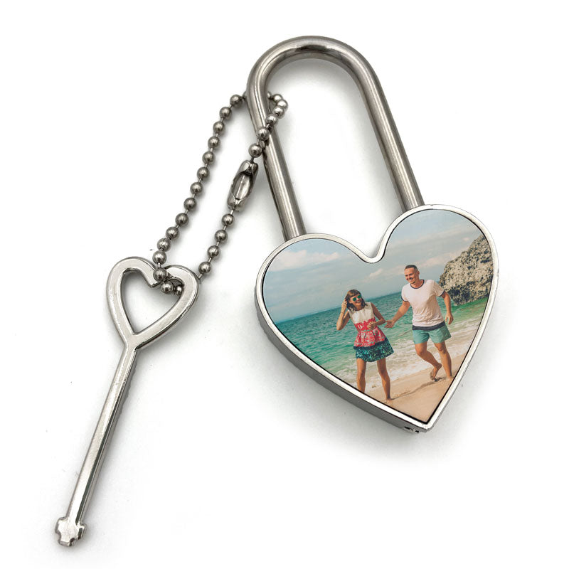 A meatal heart shaped padlock with a photo of a couple on a beach on the front and a heart shaped key.