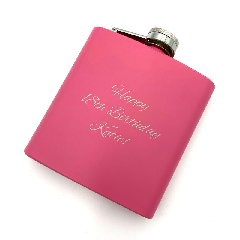 A personalised hip flask with a mat pink coating and an engraved message.