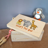 A personalised wooden toy box with a lion, an elephant and a giraffe printed on the lid. Below is space for you to add a name of your choice. The design is in full colour and the lettering is orange.