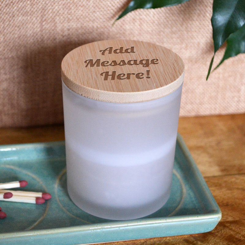 A close up of the bamboo lid on this personalised candle. The lid is engraved with the sample text 
