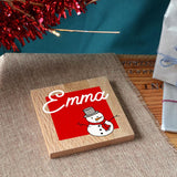 A personalised Christmas coaster in solid oak with a name and a snowman printed on the front.