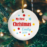 A personalised Christmas decoration celebrating a baby's first Christmas. The design is text based with red, yellow and pale blue stars around the words. 