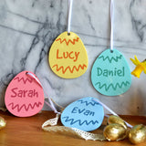 4 personalised Easter egg decorations for hanging on an Easter tree. The decorations are pink, blue, green and yellow and have a custom name printed in the centre.