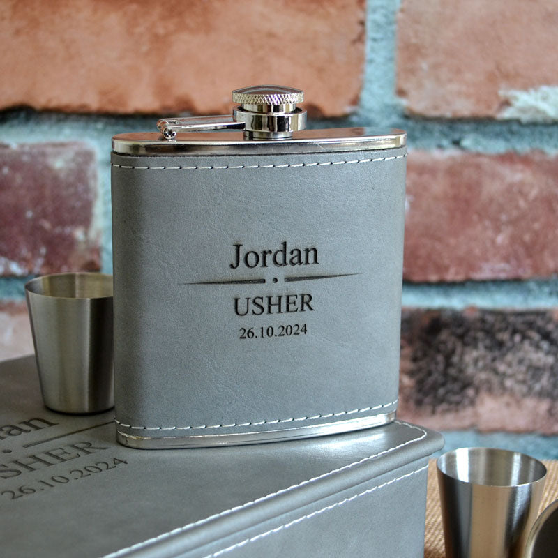 A personalised wedding hip flask in stainless steel and grey leather. The leather exterior is engraved with a name, role and wedding date. 