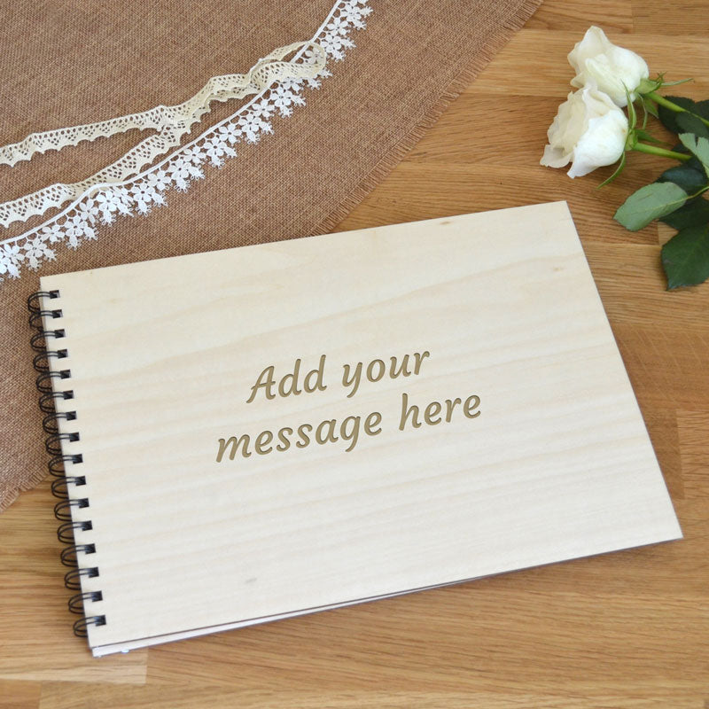 A personalised wooden covered sketchbook on a table. The front cover of the sketchbook has a message engraved into the surface of the plywood.