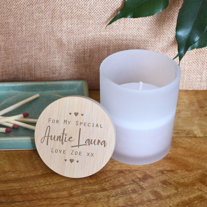A personalised candle in a glass pot with a bamboo lid. The bamboo lid is engraved with a design featuring the words 