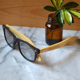 A pair of personalised sunglasses made from bamboo. The glasses have a name engraved on the side.