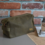 A personalised green men's wash bag in waxed cotton with custom gold initials