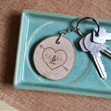  A wooden keyring engraved with a heart shape with an arrow piercing it. Within the heart are two names and a special date.